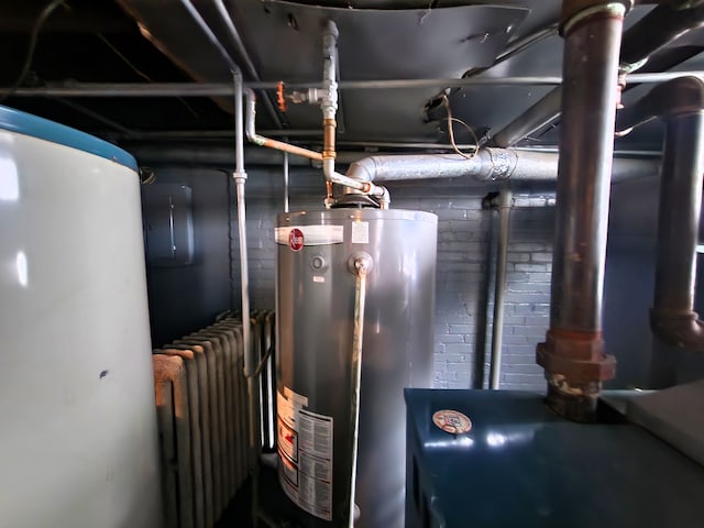 utility room featuring water heater and radiator heating unit