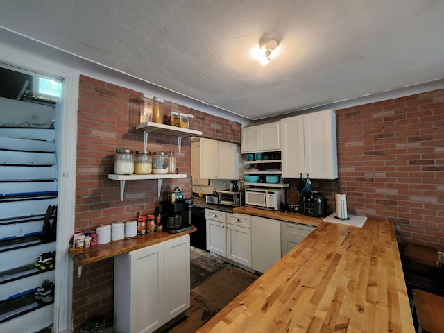 kitchen featuring wooden counters, white cabinetry, dishwasher, and brick wall