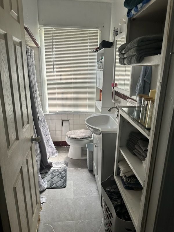 bathroom featuring vanity, tile walls, and toilet