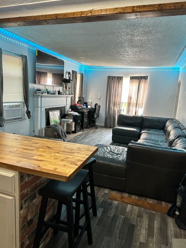 living room with a textured ceiling, cooling unit, and dark hardwood / wood-style floors