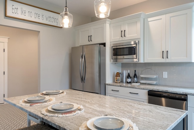 kitchen featuring light stone countertops, tasteful backsplash, decorative light fixtures, white cabinetry, and stainless steel appliances