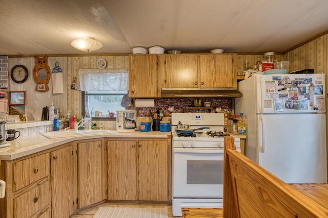 kitchen featuring wood walls, sink, and white appliances