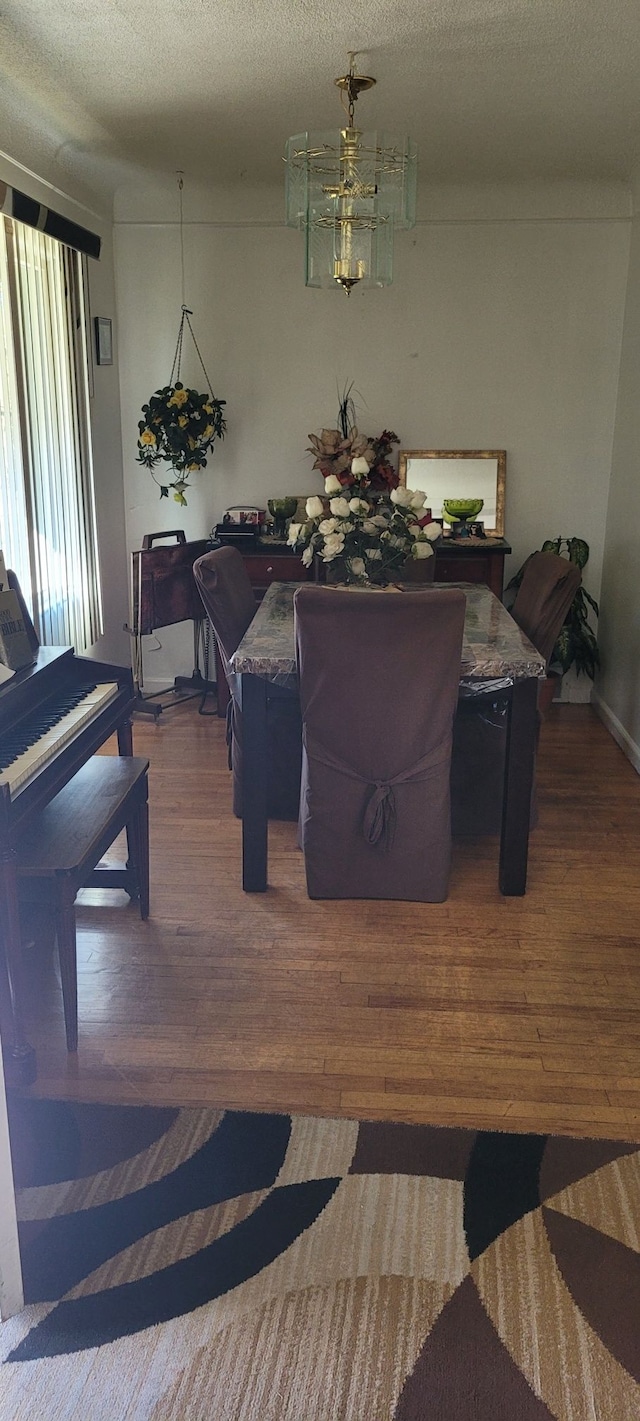 dining area featuring hardwood / wood-style floors, a textured ceiling, and an inviting chandelier