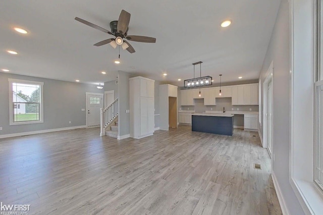 unfurnished living room featuring light hardwood / wood-style flooring, ceiling fan, and sink