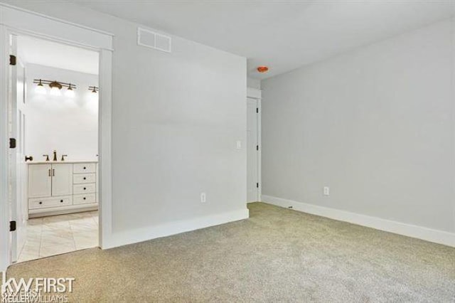 unfurnished bedroom with sink and light colored carpet