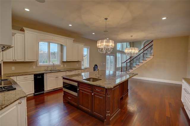 kitchen with an island with sink, sink, and white cabinets