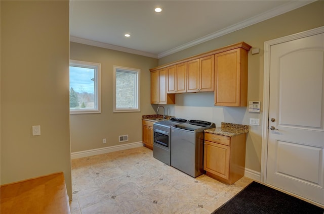 clothes washing area with washer and dryer, sink, crown molding, and cabinets