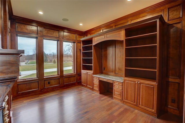 unfurnished office with built in desk, ornamental molding, dark hardwood / wood-style floors, and wooden walls