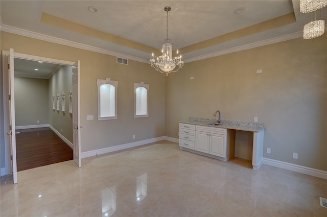 unfurnished dining area with crown molding, sink, an inviting chandelier, and a tray ceiling