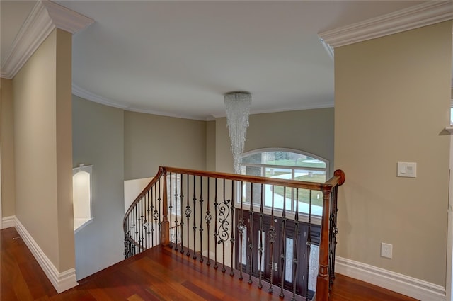 hall with hardwood / wood-style flooring, ornamental molding, and an inviting chandelier