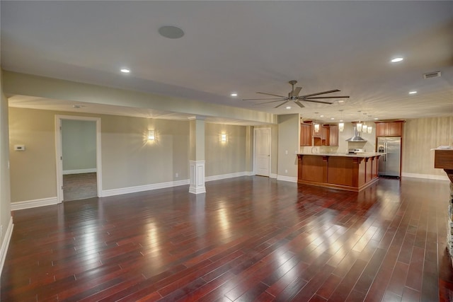 unfurnished living room with dark hardwood / wood-style floors, ceiling fan, and ornate columns