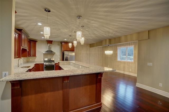 kitchen with decorative light fixtures, sink, stainless steel appliances, light stone countertops, and wall chimney exhaust hood