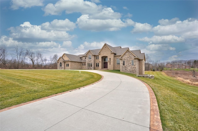 8498 Highgrove Ct, Grand Blanc, MI 48439 - french country style house with curved driveway, a front lawn, brick siding, and stone siding