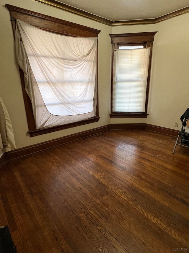 spare room featuring dark hardwood / wood-style flooring and crown molding