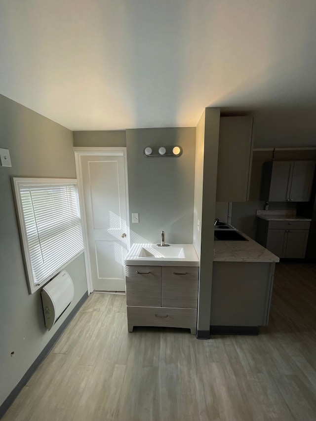 kitchen featuring light wood-type flooring, gray cabinetry, and sink