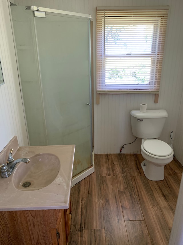 bathroom featuring vanity, wood walls, a shower with door, hardwood / wood-style flooring, and toilet