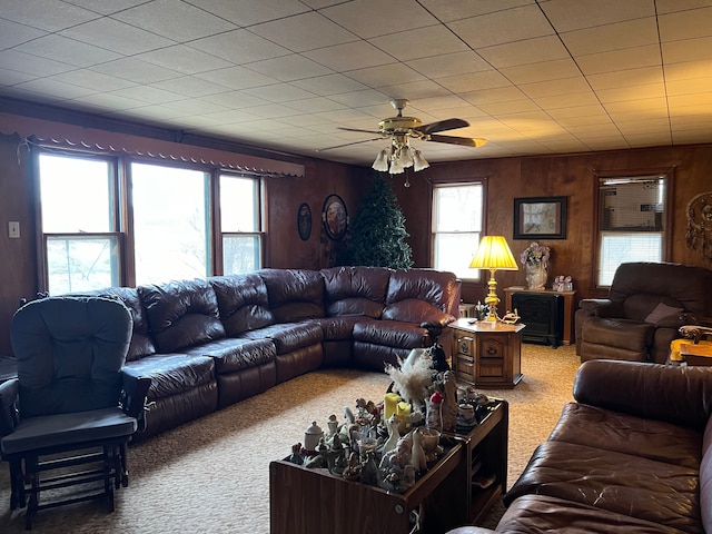 carpeted living room featuring a wealth of natural light, wooden walls, and ceiling fan