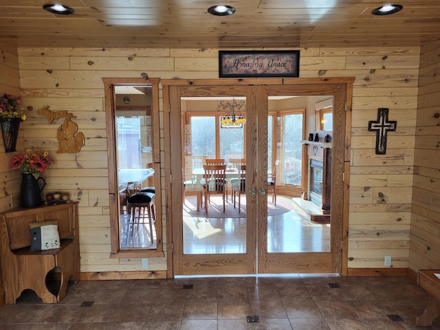 doorway featuring wooden ceiling, wooden walls, and french doors