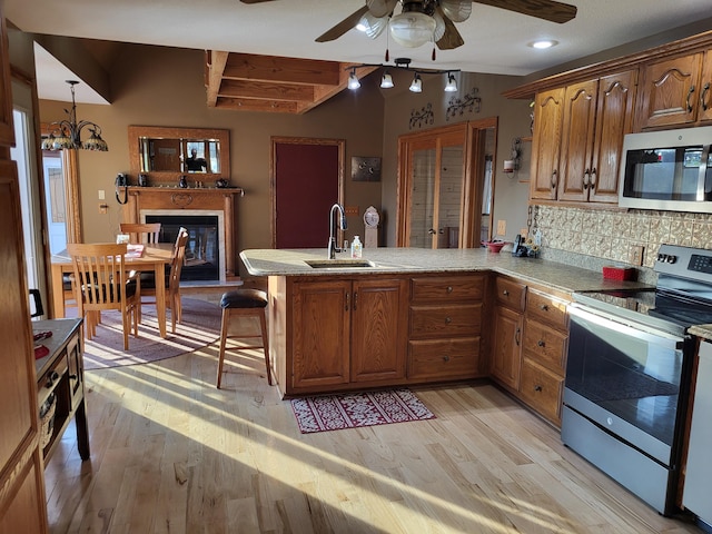 kitchen featuring kitchen peninsula, light wood-type flooring, stainless steel appliances, and sink