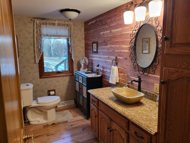 bathroom featuring hardwood / wood-style flooring, vanity, toilet, and wooden walls