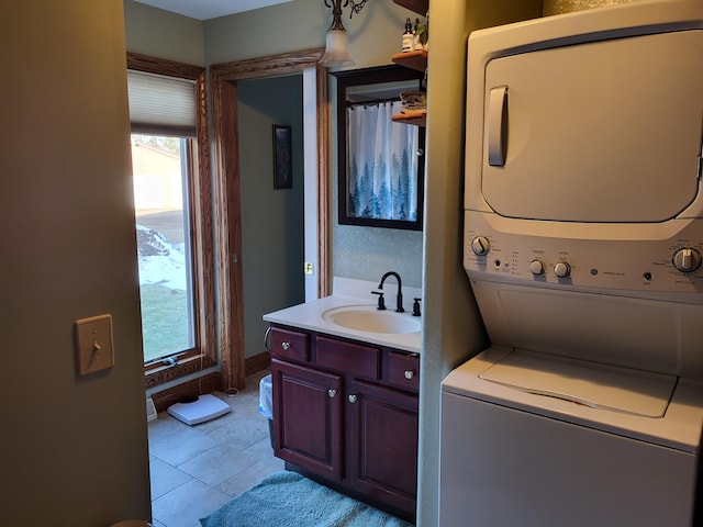 laundry area featuring light tile patterned floors, stacked washer and dryer, and sink