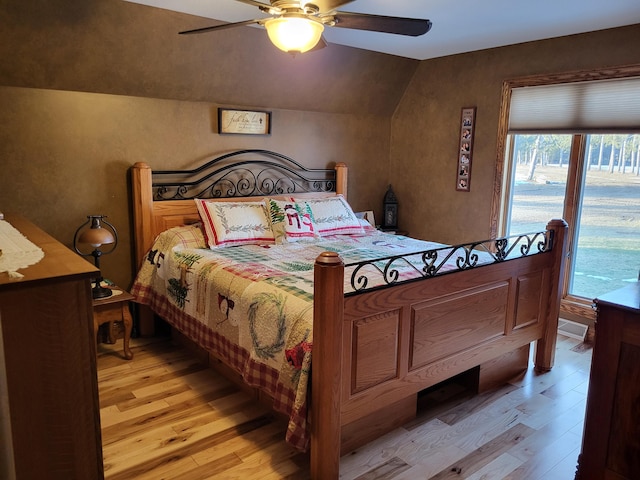 bedroom with ceiling fan, light wood-type flooring, and lofted ceiling