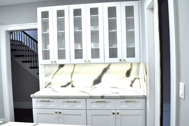 bar with light stone countertops and white cabinetry