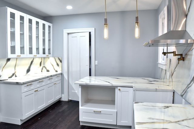 kitchen featuring dark hardwood / wood-style floors, white cabinetry, light stone counters, and wall chimney range hood