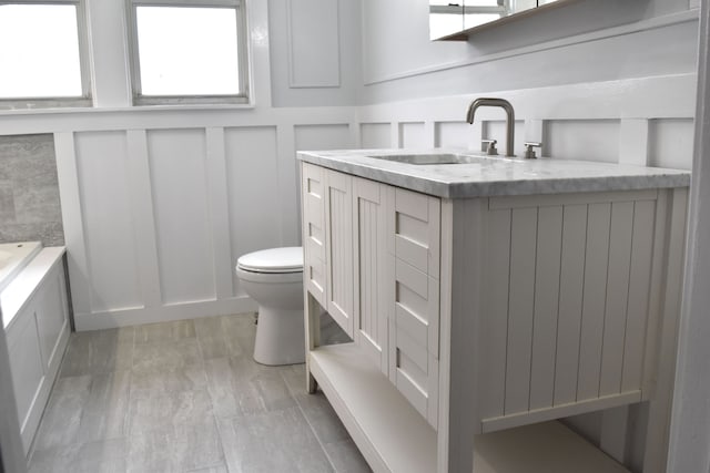 bathroom featuring a washtub, vanity, and toilet