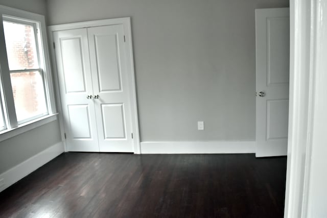 unfurnished bedroom with dark hardwood / wood-style floors and a closet