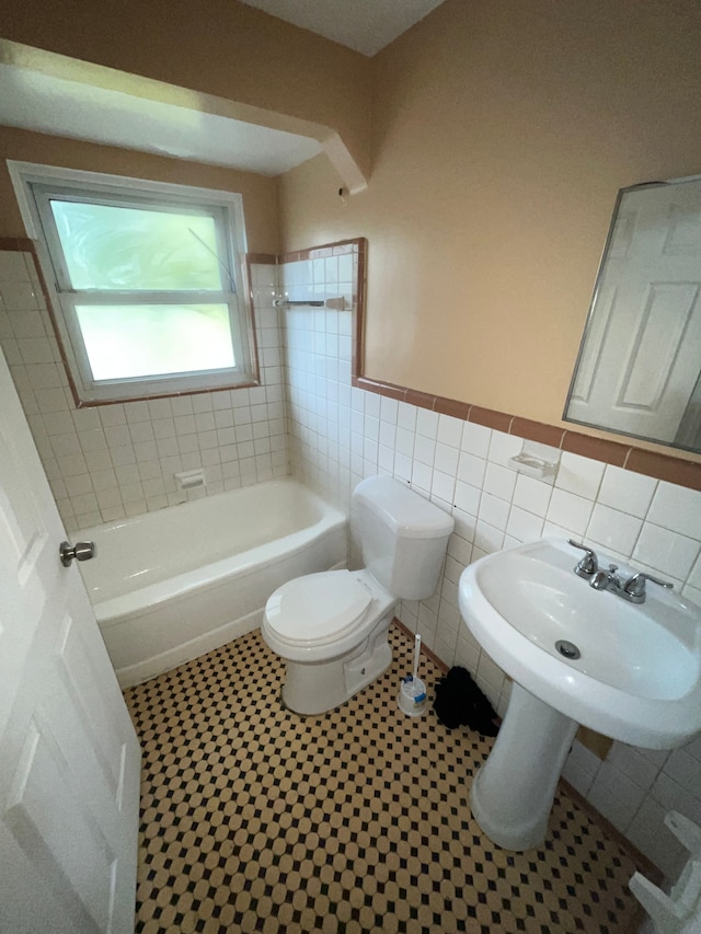 full bathroom featuring tile patterned floors, sink, tiled shower / bath, toilet, and tile walls