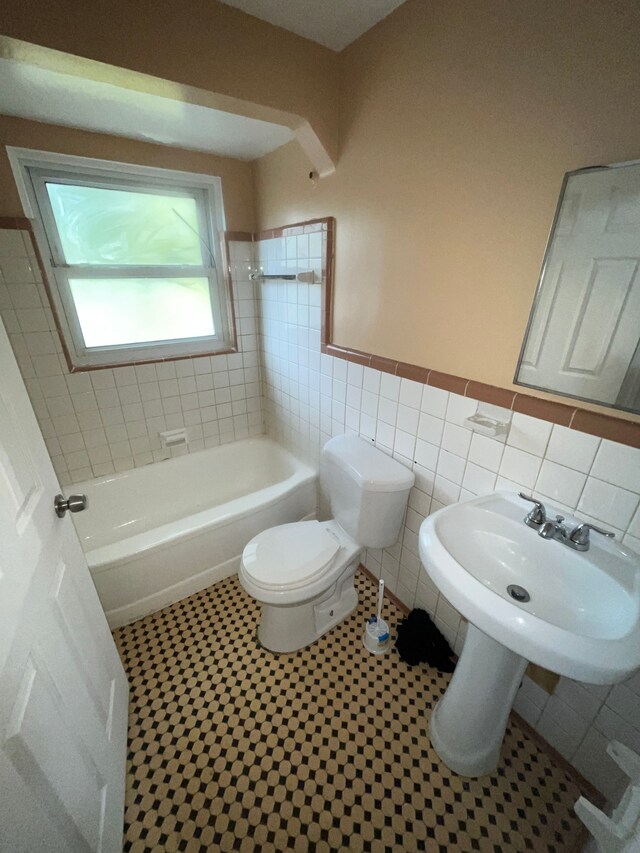 18903 Evergreen Rd, Detroit, MI 48219 - bathroom with toilet, a tub, tile walls, and a wainscoted wall