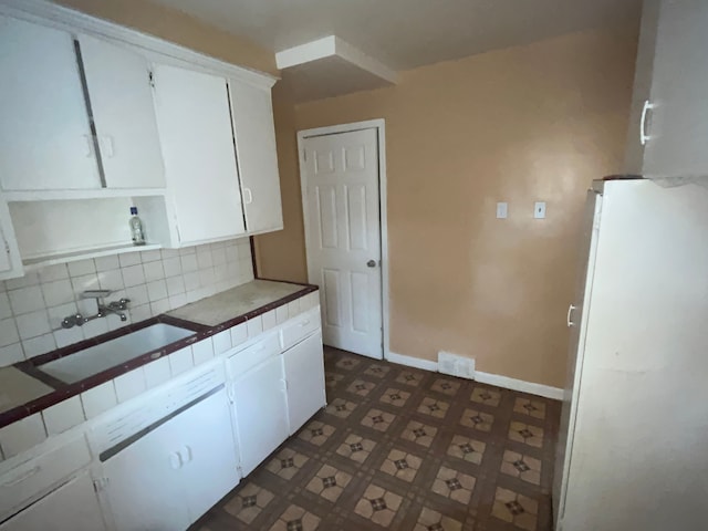 kitchen featuring backsplash, sink, white cabinets, and white refrigerator