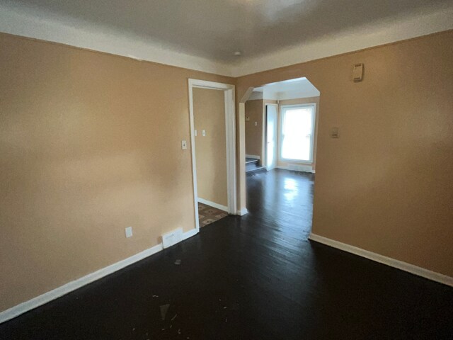 18903 Evergreen Rd, Detroit, MI 48219 - unfurnished room with arched walkways, baseboards, and dark wood-style floors