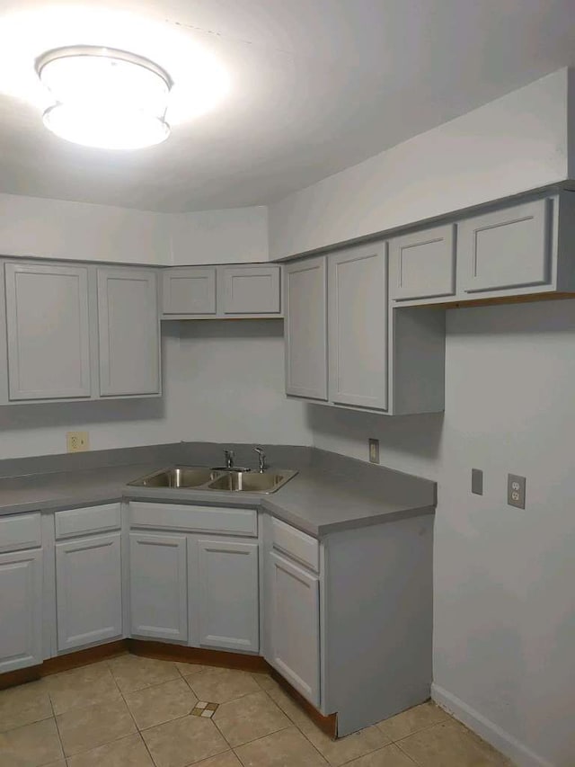 kitchen featuring gray cabinetry, light tile patterned floors, and sink