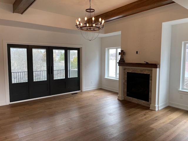 entrance foyer with a notable chandelier, beam ceiling, wood-type flooring, and french doors