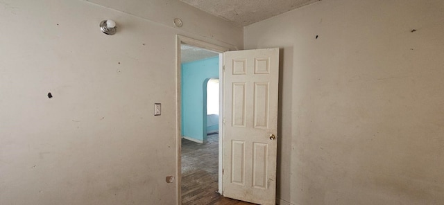 hallway with a textured ceiling and dark wood-type flooring