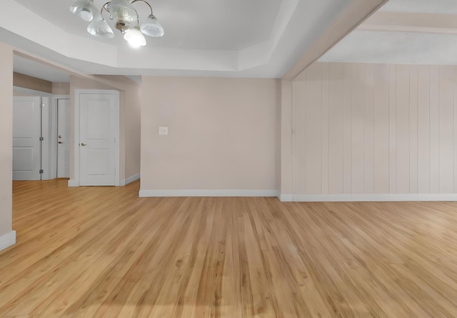 spare room featuring a tray ceiling and light hardwood / wood-style floors