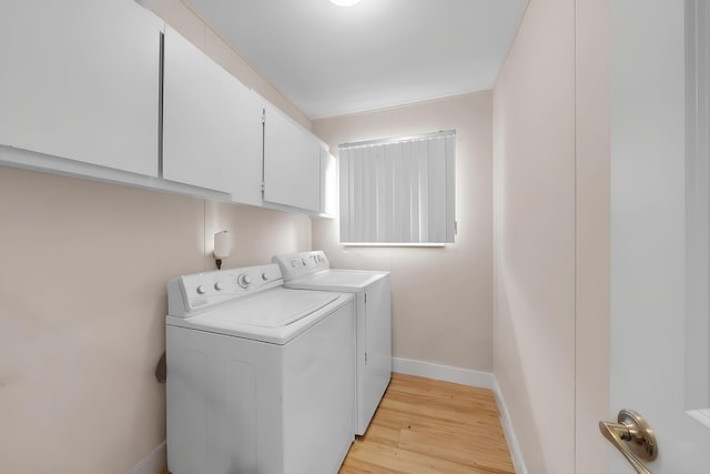 washroom featuring independent washer and dryer, light wood-type flooring, and cabinets