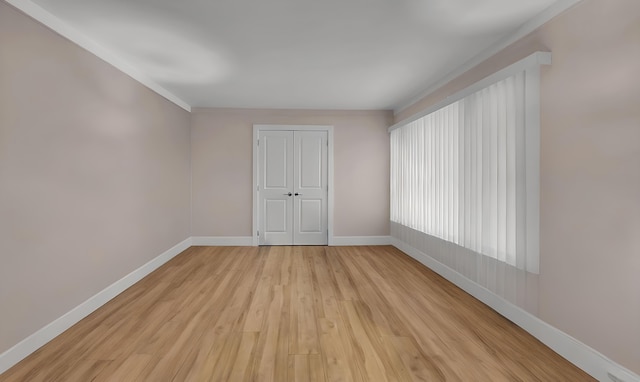 spare room with crown molding and light wood-type flooring