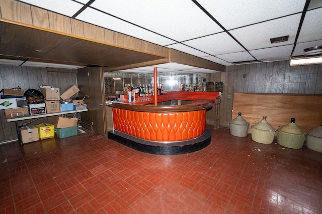 bar featuring wood walls and a drop ceiling