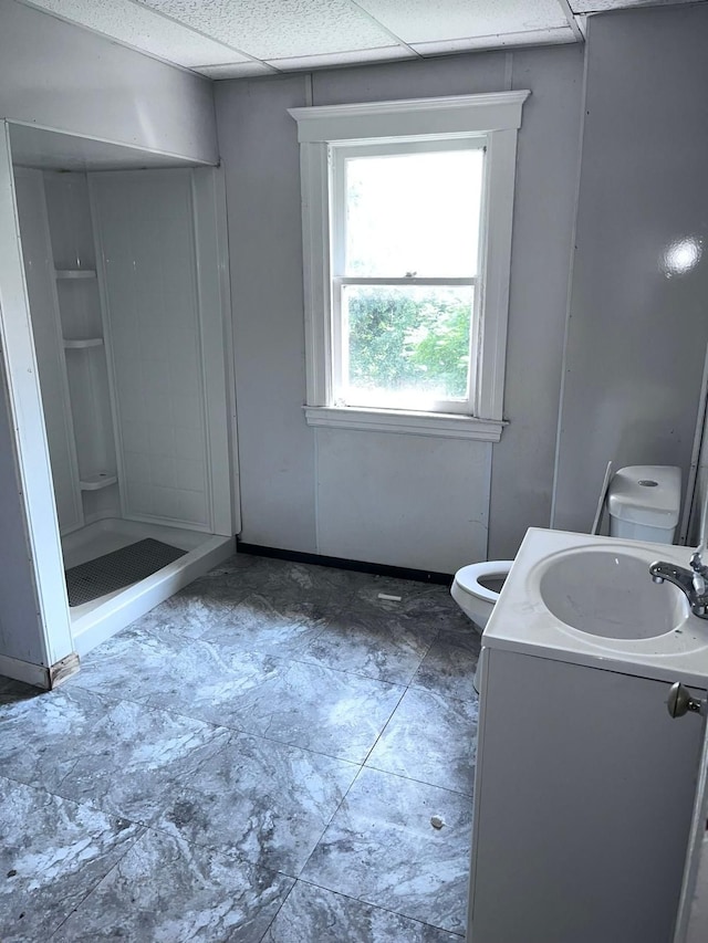 bathroom with a shower, vanity, toilet, and a paneled ceiling