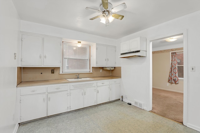 kitchen with sink, white cabinetry, ceiling fan, and light colored carpet