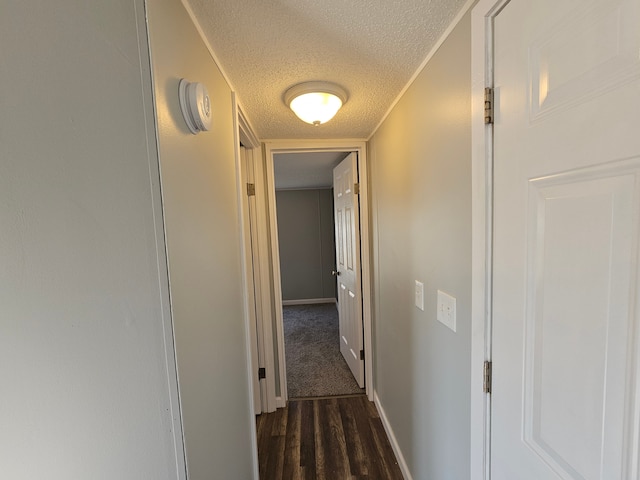 hallway featuring dark hardwood / wood-style flooring, a textured ceiling, and ornamental molding