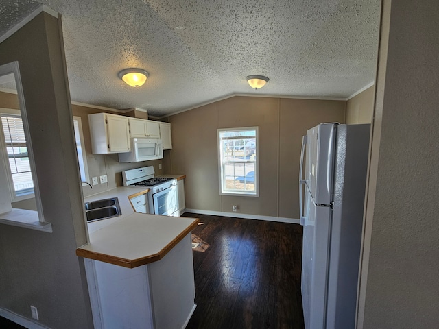 kitchen featuring lofted ceiling, white appliances, dark wood-type flooring, sink, and kitchen peninsula