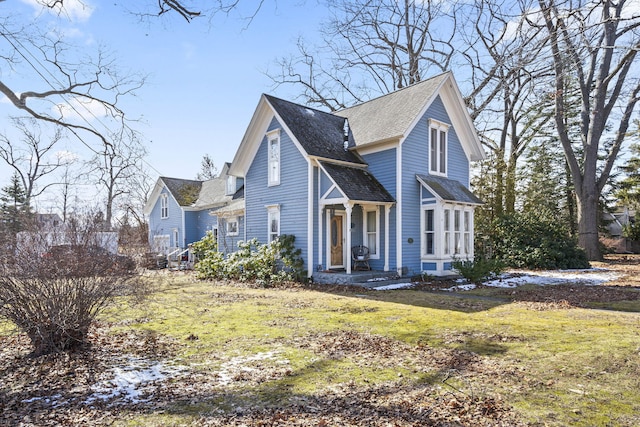 view of front facade featuring a front lawn and roof with shingles