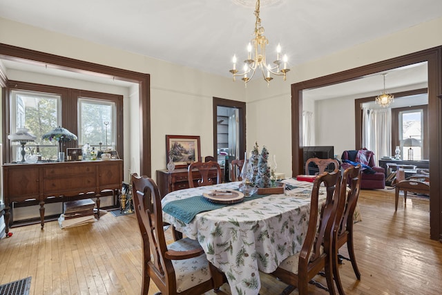 dining area with light hardwood / wood-style floors and an inviting chandelier