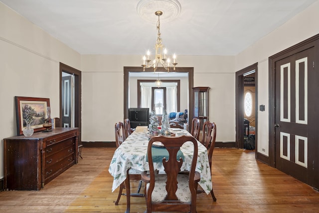 dining space with light hardwood / wood-style flooring and an inviting chandelier