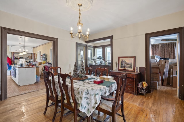 dining space with light hardwood / wood-style floors and a notable chandelier