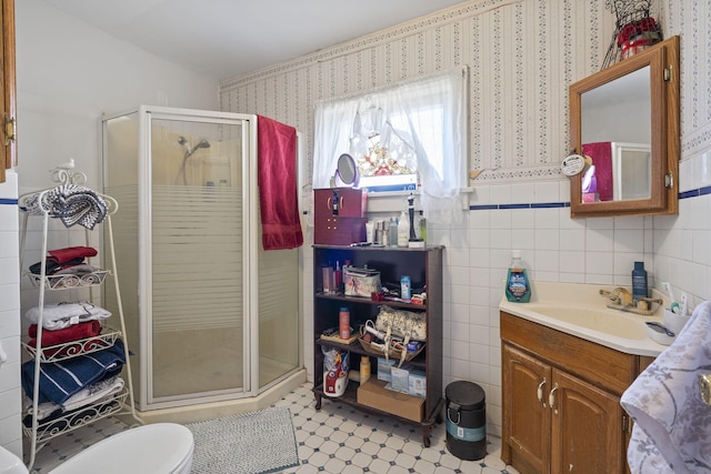 bathroom featuring vanity, toilet, an enclosed shower, and tile walls